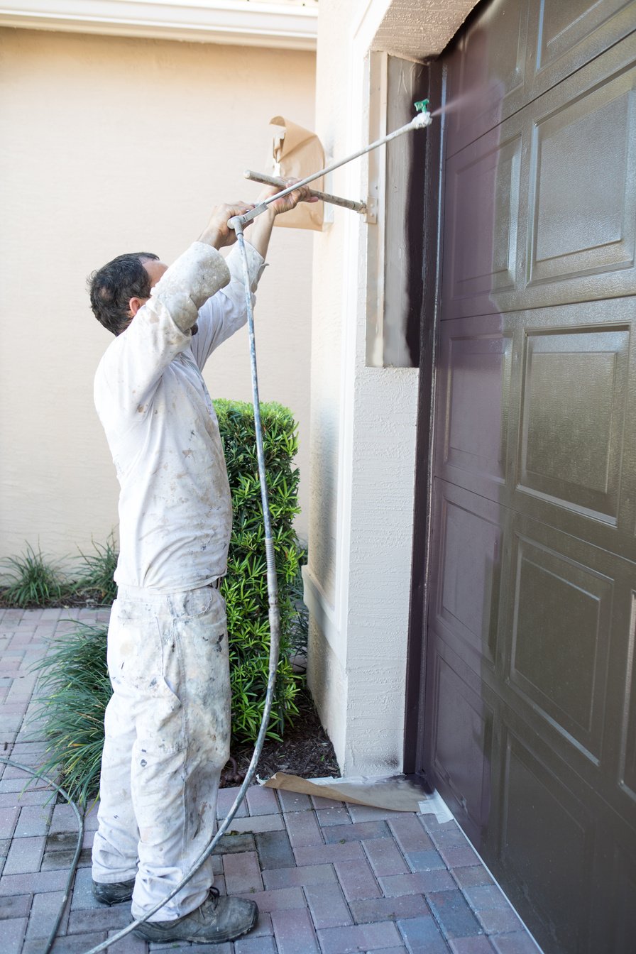 Series:Hispanic house painter painting garage door of home